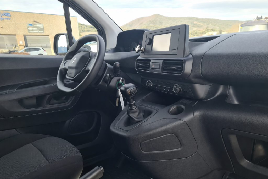 Interior de Peugeot Partner de segunda mano con salpicadero, volante y cambio manual en cabina profesional FurgoPro