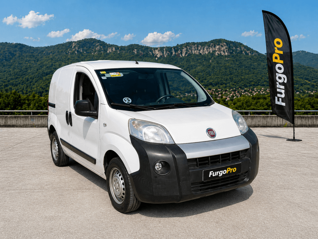 Fiat Fiorino 2016 furgon blanca vista lateral delantera segunda mano en Girona con fondo montañas Garrotxa y diseño FurgoPro profesional lista para trabajar