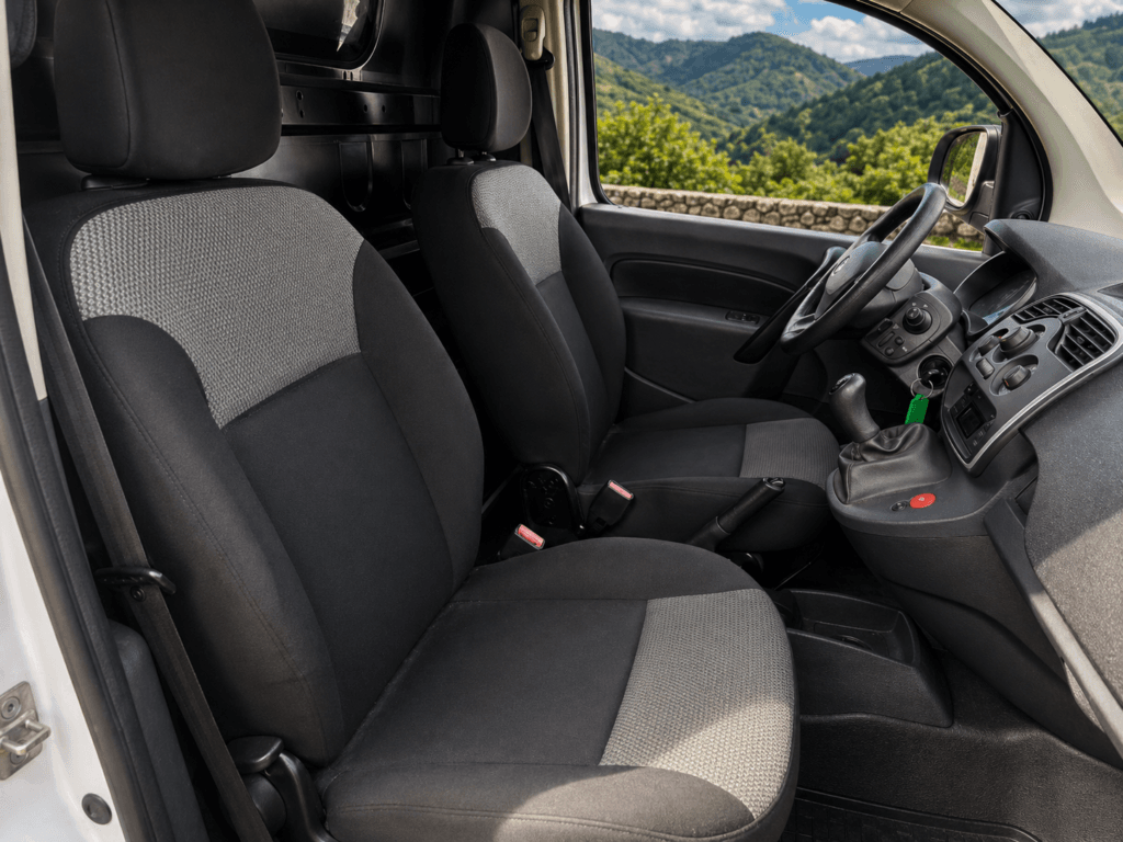 interior renault kangoo de segunda mano con asientos delanteros en buen estado y fondo natural de la garrotxa visible por el cristal
